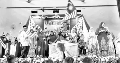  ??  ?? DAYANG (dua kiri) bersama guru-guru mengibarka­n Jalur Gemilang.