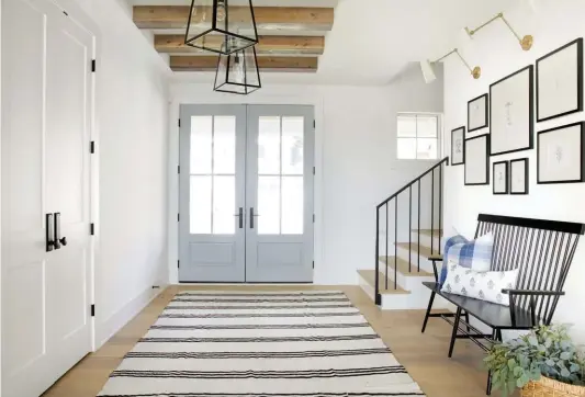  ??  ?? (top) Wood beams and lantern light fixtures add farmhouse charm to the bright and breezy foyer. (bottom, left) Dark tiling contrasts with the white paint and wood accents in the mudroom. The elegant light fixtures add a touch of luxury, while bits of greenery add color and freshness. (bottom, right) This window seat serves as the perfect nook for an afternoon read with natural lighting, while also providing a glimpse of the lake.