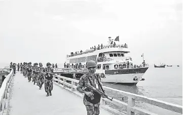  ??  ?? Border Guards Bangladesh paramilita­ry personnel carrying assault rifles disembark as they have been deployed on Saint Martin’s island, a small island in the Bay of Bengal in Teknaf. — AFP photo