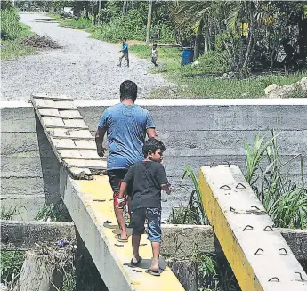  ?? FOTO: SAMUEL ZELAYA ?? PASO. Los habitantes de unas cuatro colonias del sector este hacen malabares para poder cruzar por las vigas de concreto y una tabla, a tal grado que han sufrido caídas.