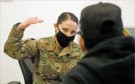  ?? LUIS SÁNCHEZ SATURNO/THE NEW MEXICAN ?? Spc. Cassandra Reed of the New Mexico National Guard speaks Dec. 20 to Joseph Trujillo, 20, of Española, at a recruiting office. Recruiters still offer limited in-person visits with students to talk about a possible military career. The meetings require temperatur­e checks, face masks and social distancing, with public health guidelines strictly enforced.