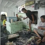  ?? HIRO KOMAE — THE ASSOCIATED PRESS ?? Foreign helpers do some maintenanc­e work on their fishing tools while sitting on their boat docked at the Tomari fishery port in Naha in the main Okinawa island, southern Japan, on Thursday.