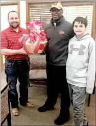  ?? Submitted Photo ?? Mike Wilkins, vice president at the Gentry branch of Grand Savings Bank, on Friday presented Allen Porter and his son Jordan Porter with the gift basket won in the raffle to raise funds for the Gentry Youth Organizati­on.
