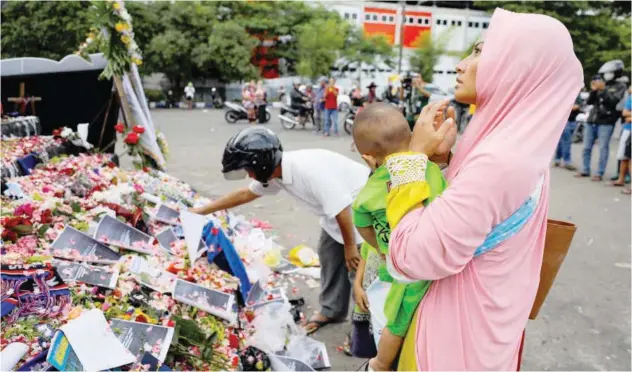  ?? Reuters ?? ±
A woman, carrying her child, prays for the victims of the soccer stampede outside the Kanjuruhan stadium in Malang, Indonesia, on Monday.