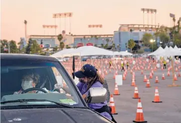  ?? PHILIP CHEUNG/THE NEW YORK TIMES ?? Maria Rivera gets a COVID-19 vaccine injection Thursday at Dodger Stadium. Los Angeles County officials say the call for testing has collapsed. Not long ago, the county was conducting over 350,000 tests weekly.