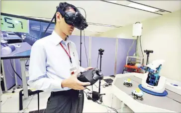  ?? THE YOMIURI SHIMBUN ?? A person wearing a VR headset operates a robot arm as part of NTT Docomo’s 5G experiment in Yokosuka, Kanagawa prefecture.