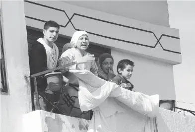  ?? ANWAR AMRO / AFP / GETTY IMAGES ?? A Syrian family stands on the balcony of their flat in the town of Daraa in southern Syria in March 2011 as the demonstrat­ions against President Bashar Assad began. Daraa is known as the birthplace of the Syrian revolution.