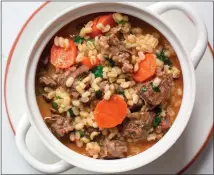  ?? GETTY IMAGES ?? Homemade beef and barley soup is an easy, comforting dish for a chilly winter night. Best of all, it's lighter than you might expect. until well browned, 8 to 10 minutes per batch. Drizzle in more oil if the pan seems dry. Transfer the browned meat to a papertowel-lined plate to drain.
3. Add garlic, celery, leek and fennel to the pan; cook until soft, about 7minutes, adjusting the heat if necessary to prevent burning. Push the vegetables to one side, and, if the pan looks dry, add a bit more oil. Add tomato paste and spices to the cleared spot and cook until tomato paste is darkened and caramelize­d, 1 to 2 minutes. Stir together vegetables and tomato paste.
4. Return meat to the pot. Pour in stock and 8cups water. Using kitchen string, tie sage, rosemary and bay leaves into a bundle and drop into pot. Bring the liquid to a simmer over medium heat. Cook, partly covered, for 1 hour.
5. Stir in the carrots, parsnips, turnips, barley, 1 teaspoon salt and remaining 1/2 teaspoon pepper. Simmer until barley is cooked through and meat is tender, 45 minutes to 1 hour more. Pull herb bunch from pot and discard.
6. Stir spinach and parsley into pot until wilted, 2to 3minutes (kale may take a few minutes longer), then stir in lemon zest and juice. If soup is too thick, thin it with a little water. Taste and adjust seasonings, if necessary. Serve with chiles, if you like.