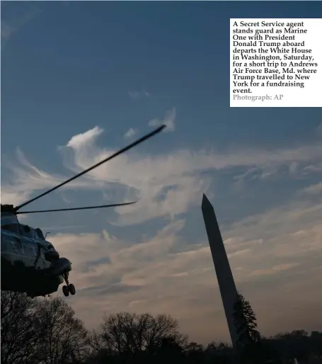  ?? Photograph: AP ?? A Secret Service agent stands guard as Marine One with President Donald Trump aboard departs the White House in Washington, Saturday, for a short trip to Andrews Air Force Base, Md. where Trump travelled to New York for a fundraisin­g event.