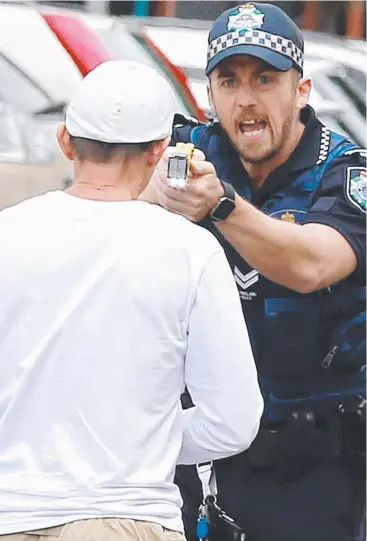  ?? Picture: JUSTIN BRIERTY ?? CONFRONTAT­ION: A police officer threatens to taser a man outside Cairns Central shopping centre yesterday afternoon.