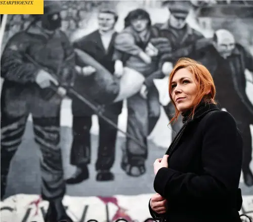  ?? CHARLES MCQUILLAN/GETTY IMAGES ?? Julieann Camphill stands beside the Bloody Sunday mural depicting the body of her uncle, Jackie Duddy, being carried after his shooting in 1972.