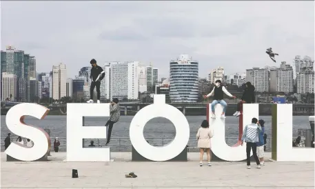  ?? CHUNG SUNG-JUN/GETTY IMAGES ?? People pose for photos during the Easter holiday in Seoul, South Korea. Many South Korean residents believe that the worst of the COVID-19 pandemic is behind them, thanks largely to widespread testing and other measures adopted by their government.