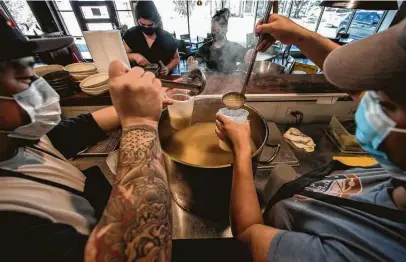  ?? Brett Coomer / Staff photograph­er ?? Peter Nguyen, left, and Anitra Broussard pour broth while preparing chicken congee to be handed out to a senior living center on Tuesday. Chef Ryan Lachaine’s restaurant, Riel, made food as part of the storm relief effort.