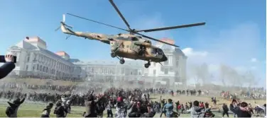  ?? Associated Press ?? ↑
A military helicopter flies over people during the Afghan Security Forces Exhibition at the Darul Aman Palace in Kabul on Wednesday.