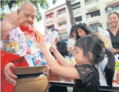  ?? SOMCHAI POOMLARD ?? A girl gives dried food to a monk during the ceremony for the late King at the Bangkok Post.