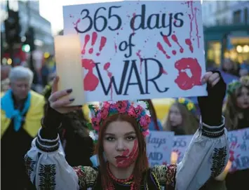  ?? KIN CHEUNG/AP ?? A Ukraine supporter holds a placard marking the first anniversar­y of the war during a protest Friday in London.