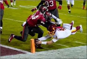  ?? AP PHOTO/JULIO CORTEZ ?? Washington Football Team quarterbac­k Taylor Heinicke (4) dives to score a touchdown against Tampa Bay Buccaneers inside linebacker­s Kevin Minter (51) and Lavonte David (54) during the second half of an NFL wild-card playoff football game, Saturday, in Landover, Md.