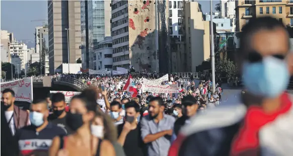  ?? Reuters ?? Thousands of people march in Beirut yesterday to mark one year since the beginning of nationwide anti-government protests