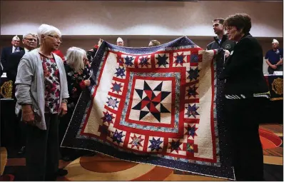  ?? Arkansas Democrat-Gazette/THOMAS METTHE ?? Connie Wilson and her sister, Carol Erdmann, present to members of the American Legion Auxiliary a quilt made by their mother, Ruth Legan, before she died last year. The sisters appeared at an American Legion conference in North Little Rock on Saturday.