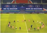  ?? XAVIER LAINE POOL/AFP VIA GETTY IMAGES ?? Referees join PSG and Basaksehir players in kneeling on the pitch against racism before their match Wednesday.