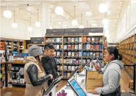  ?? THE ASSOCIATED PRESS ?? Customers buy a bag of books at an Amazon Books store Monday in New York. Amazon goes into the holiday season with a newly magnified brick-and-mortar presence, giving it more opportunit­ies to sell its Kindle e-readers, Fire tablets and other gadgets.