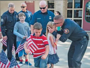  ??  ?? (Top) Niki Tomlinson, left, takes a photograph of her 1-year-old son Lincoln while Camryn Masters, center, and Naomi Richardson count flags displayed for “Patriot Day” on Friday. Trinity Classical Academy in Santa Clarita presented a “9/11 Never Forget...