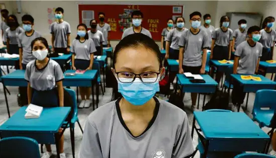  ?? Edgar Su/Reuters ?? Estudantes, com máscaras e com espaçament­o maior entre as carteiras, em sala de aula na escola Yio Chu Kang, reaberta em Singapura