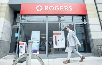  ?? LAURA PEDERSEN/NATIONAL POST ?? A man walks past a Rogers store in Toronto. Rogers’ stock price hit a record high Thursday after it reported its first set of quarterly results since CEO Joe Natale took over in April.