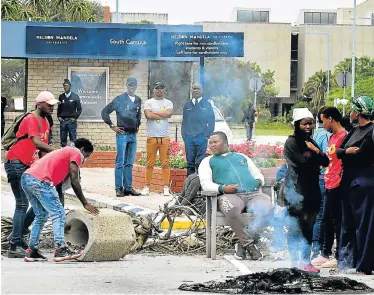  ??  ?? NO ENTRY: Protesting Nelson Mandela University students block the entrance to the south campus as protest action enters its second day. About 400 protesters put down rocks and branches to prevent people from entering both the south and north campuses