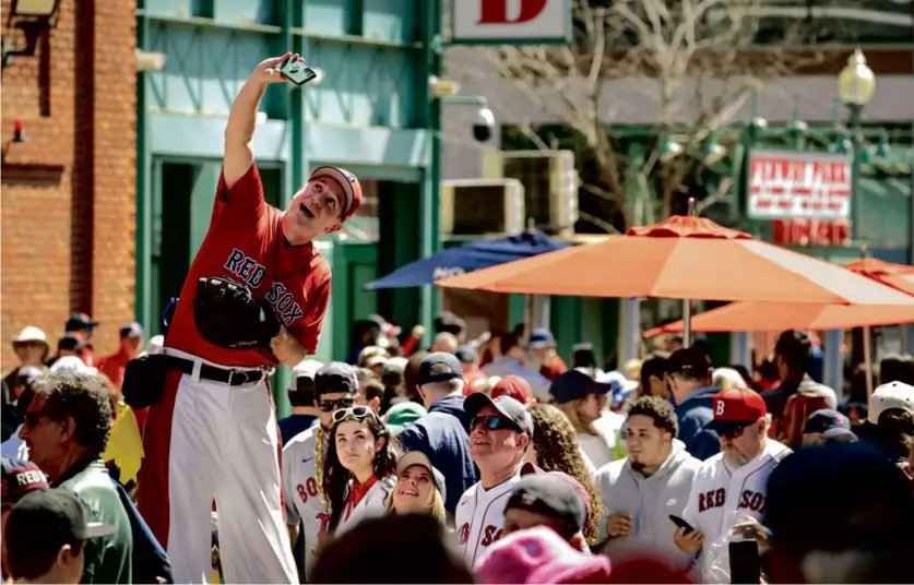  ?? PHOTOS BY CRAIG F. WALKER/GLOBE STAFF ?? It was a festive scene outside Fenway Park Tuesday as fans gathered for Opening Day. “Big League Brian” (above) entertaine­d the crowd and took a selfie while Dennis Brophy (top left) carried his son, Theo, on his shoulders. Ben Stecher (top middle) kept an eye out for arriving players while a group of fans (top right) tried to get an autograph.