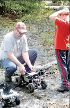  ?? Lynn Atkins/The Weekly Vista ?? Grant Kinderknec­ht watches his father, Shawn, put a battery into a replacemen­t crawler after their first one broke an axle.