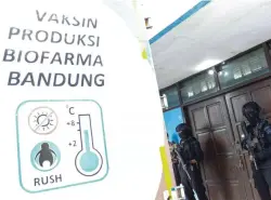  ?? ALFIAN RIZAL/JAWA POS ?? IKHTIAR ANTIKORONA: Anggota Brimob berjaga saat pengangkut­an vaksin Covid-19 Sinovac menuju cold storage di kantor Dinas Kesehatan Jawa Timur. Pemkot Surabaya juga menyiapkan lemari pendingin di kawasan Rungkut untuk menjaga vaksin.