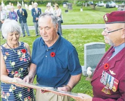  ??                              ?? Veteran Terry Randall, from right, looks over a photo album containing pictures of Gordon Stewart with Stewart’s brother Brian and sister Kate Reeves prior to a sunset wreath laying ceremony in the Wood Islands Presbyteri­an Cemetery on Saturday.
