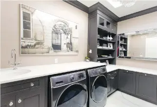  ??  ?? Sarah Baeumler’s laundry room is dressed to the nines with black cabinetry, marble floors and art on the wall.