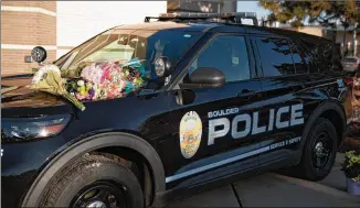  ?? THEO STROOMER/THE NEW YORK TIMES ?? Flowers laid across the hood of a police vehicle become a makeshift memorial outside the Boulder Police Department on Tuesday to honor slain Officer Eric Talley, 51, who was killed in a mass shooting at a grocery store Monday. The shooting left 10 people dead.