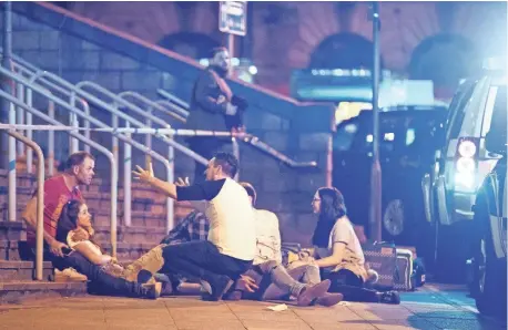  ?? REX FEATURES ?? People converse Monday evening outside Manchester Arena, where officials said a suspected suicide bomber killed at least 19 people and injured 50 others.