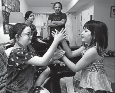  ?? TERRENCE ANTONIO JAMES/CHICAGO TRIBUNE ?? Lucca Reinoso, left, plays with her sister, Maya, as their parents look on. Lucca is asking for a cellphone, but her parents are reluctant to give her one.