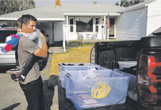  ?? Leah Millis / The Chronicle ?? Brian Padgett, 43, hugs daughter Ava, 6, tight as the family, which lost everything when they fled into the night, sorts donated items at a friend’s home.