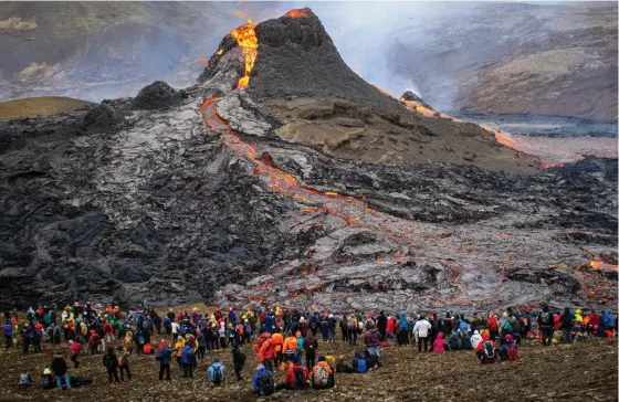  ?? FOTO: JEREMIE RICHARD/LEHTIKUVA/AFP ?? Besökare vid Fagradalsf­jäll på Island betraktar lava som strömmar från vulkanen. Nu har alla besökare evakuerats.