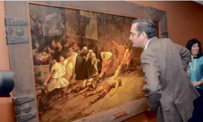  ??  ?? National Museum director Jeremy Barns unveils and inspects “Spoliarium” at León Gallery. It turns out to be a copy made by Antonio Dumlao, who restored Luna’s masterpiec­e in 1960.