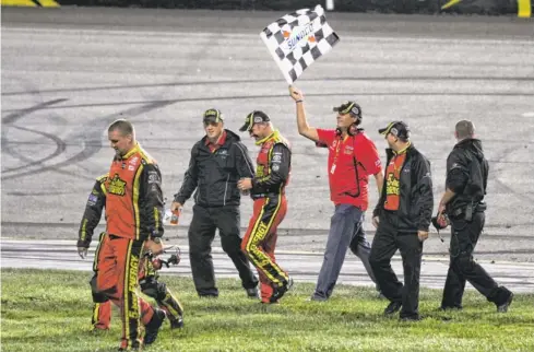  ?? JERRY MARKLAND, GETTY IMAGES, FOR NASCAR ?? Driver Clint Bowyer, center, celebrates his win Sept. 8 with members of his crew as team owner Michael Waltrip waves a checkered flag.