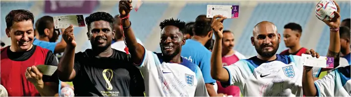  ?? ?? Joy: Thrilled migrant workers wear signed shirts yesterday and show off tickets for the match against Iran after kickabout with Harry Kane and other stars