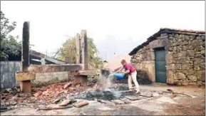  ?? FRANCISCO LEONG/AFP AFP ?? A woman pours water over a burnt area in Vila Nova near Vouzela as wildfires continue to rage in Portugal on Monday.