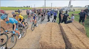  ??  ?? Geraint Thomas se duele, mientras en la imagen de al lado pasa junto al resto del pelotón después de que se despejara el camino de las balas de paja.