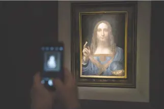  ?? AFP ?? A VISITOR takes a photo of the painting Salvator Mundi by Leonardo da Vinci at Christie’s New York Auction House, Nov. 15, in New York City.