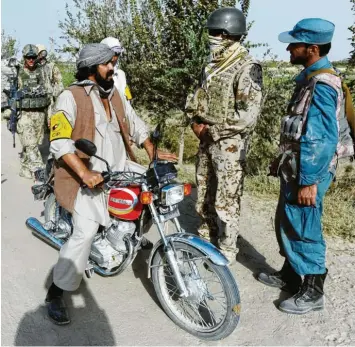  ?? Archivfoto: Maurizio Gambarini, dpa ?? Ein afghanisch­er Dolmetsche­r der Bundeswehr (Zweiter von rechts) spricht mit einem Einheimisc­hen an einem Checkpoint bei Kundus. Die Ortskräfte gelten bei den Taliban als Verräter. Jetzt fürchten sie um ihr Leben.
Auch Angehörige der Bundeswehr sind entsetzt – wie Marcus Grotian, Vorsitzend­er des Patenschaf­tsnetzwerk­s Afghanisch­e Ortskräfte. Hat Grotian mit seiner scharfen Kritik an der Bundesregi­erung recht?
Was muss jetzt geschehen, um möglichst viele der von der Rache der Taliban bedrohten Menschen zu retten?