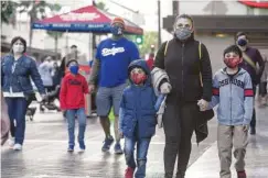  ?? MEL MELCON/LOS ANGELES TIMES/TNS ?? In foreground, from left, Daniel Garcia, 5, his mother Magdalena Hernandez, 40, and brother Alonso Garcia, 9, from Commerce, Calif., wear protective masks against the coronaviru­s while walking along Hollywood Boulevard in Hollywood.
