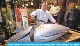  ??  ?? TOKYO: President of sushi restaurant chain Sushi-Zanmai, Kiyoshi Kimura, displays a 190-kilogram bluefin tuna at his main restaurant near Tokyo’s Tsukiji fish market. — AFP