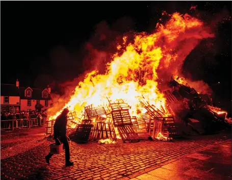  ?? Picture: Andrew Wilson/ Alamy ?? The traditiona­l Biggar bonfire blazes on Hogmanay after being lit by resident Alan Michie in 2018