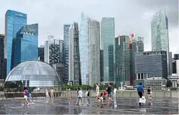  ?? — AFP ?? Hugely popular: People gather on the boardwalk at Marina bay in Singapore. the country, along with its regional peers, is witnessing a broad-based interest from some of the world’s biggest deal drivers in healthcare, infrastruc­ture and the consumer space.